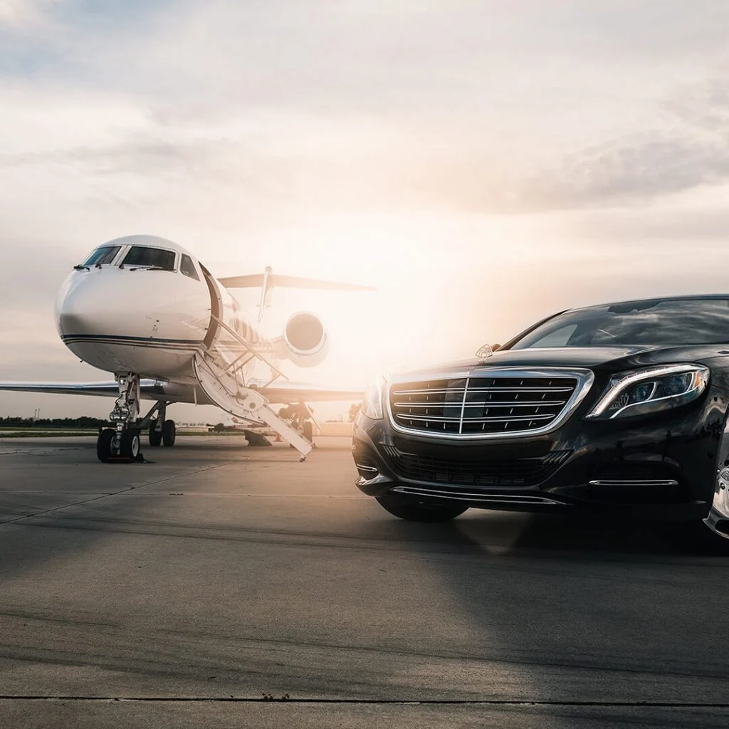 Black Mercedes sedan waiting beside a private jet